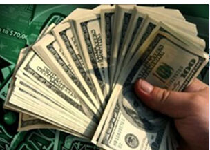 A hand holding a large bundle of US dollar bills